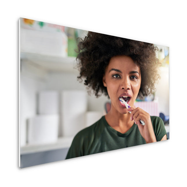 800 watt ECAROS infrared mirror with the reflection of a woman brushing her teeth, efficient and stylish heating solution for the bathroom.