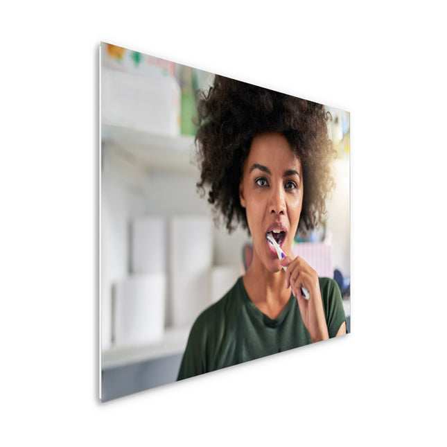 600 watt ECAROS infrared mirror with the reflection of a woman brushing her teeth, efficient and stylish heating solution for the bathroom.